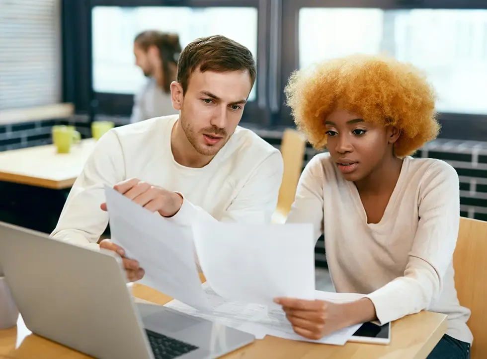 Two colleagues talking in front of a laptop